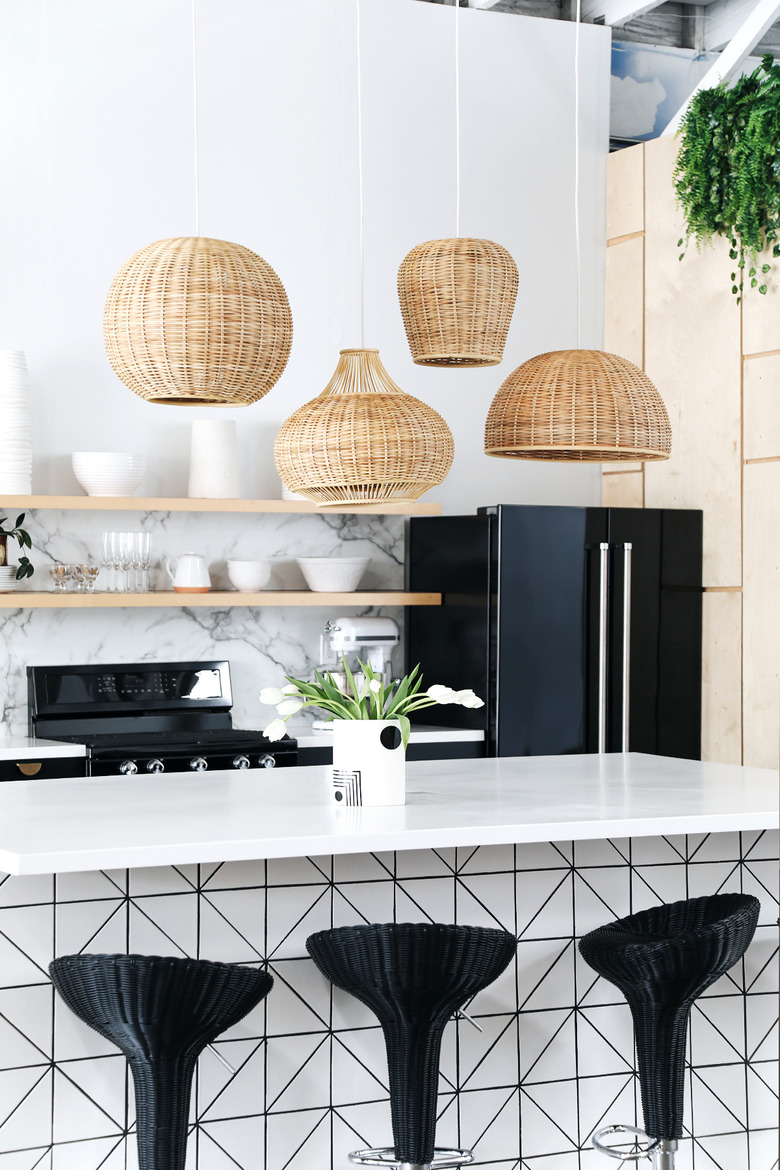 woven wicker pendant lights in various shapes above black and white modern island