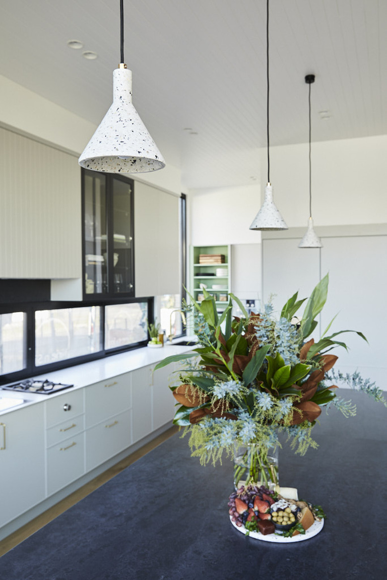 white terrazzo pendant lights above black island with fresh flowers