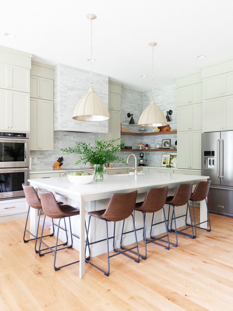 cream bell style pendant lights hanging above island with seating