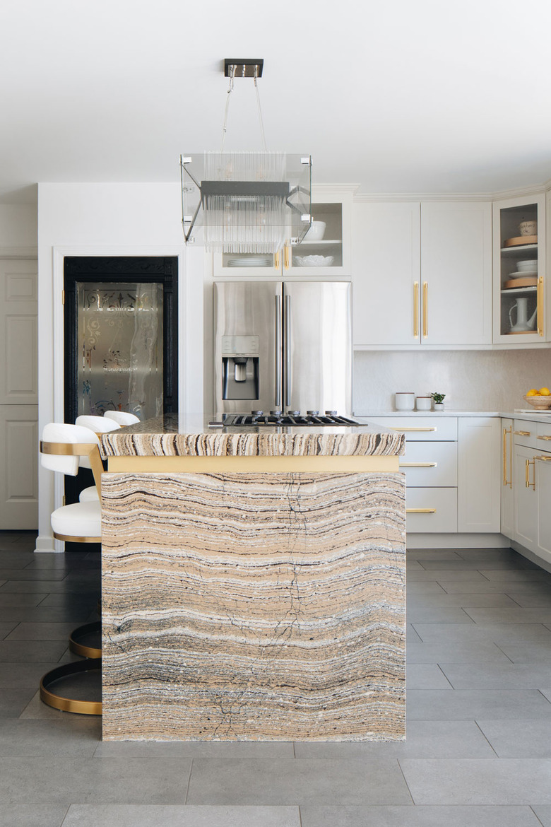 modern glass chandelier above brass and marble island