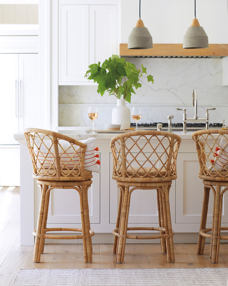 concrete pendant lights in white kitchen with rattan bar stools