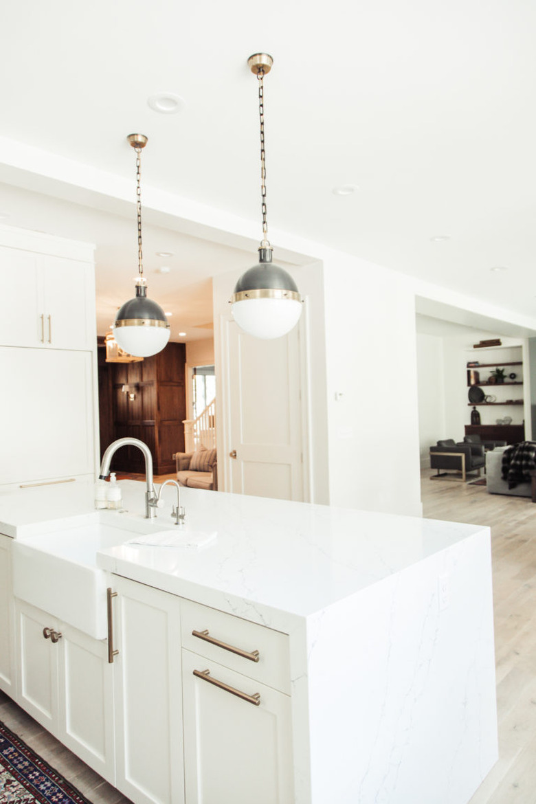 white and brass globe style pendant lights above white island