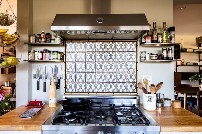 Kitchen with stainless steel oven and oven hood with tile backsplash and gray walls
