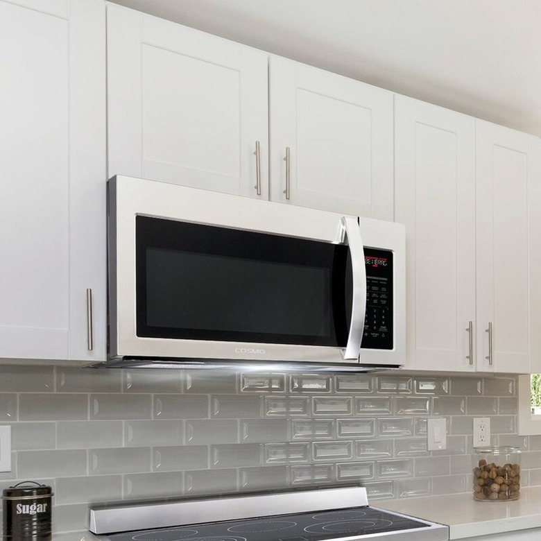 Over-the-range microwave with vent fan in a white kitchen with a gray glass tile backsplash