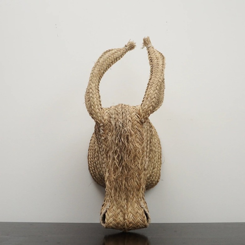 Handwoven sculpture of a donkey made of straw on a white wall