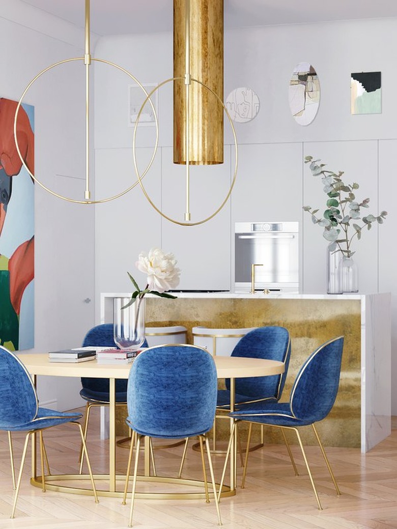 Gold ceiling light over dining table with blue chairs.
