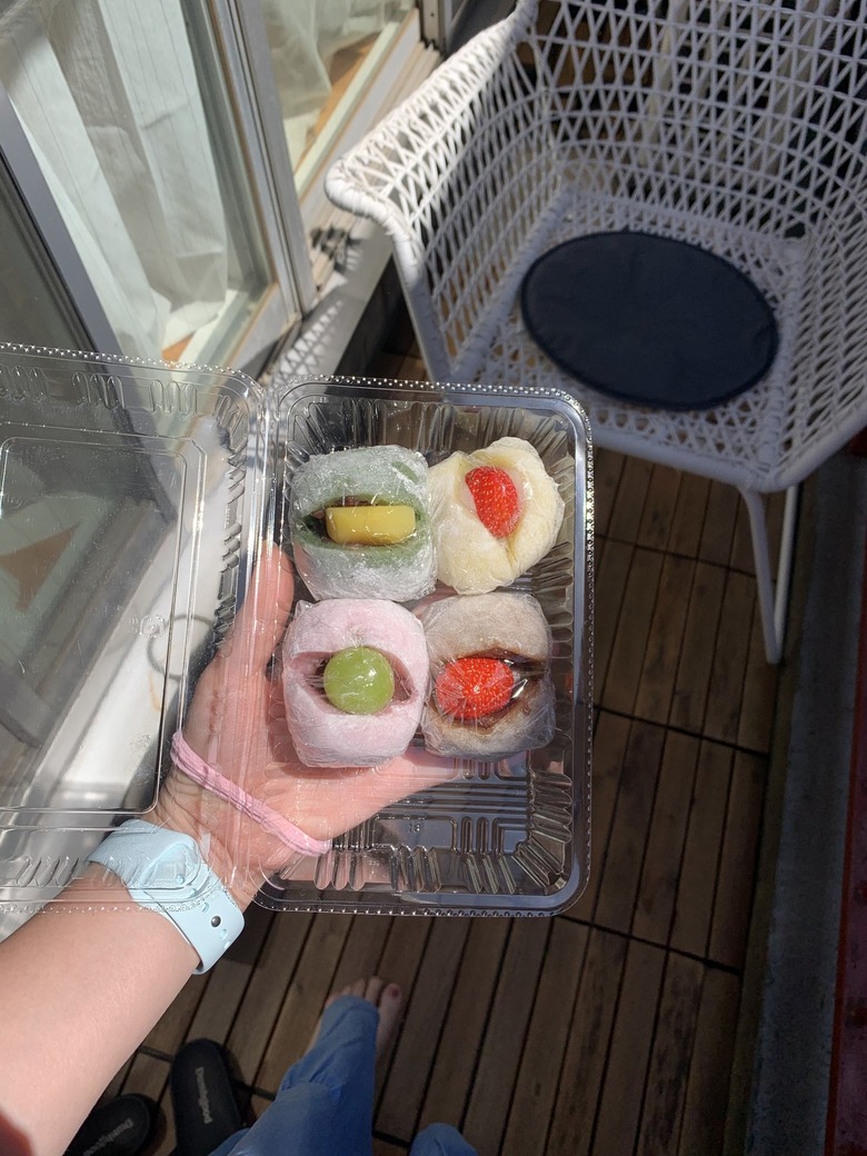 overhead shot of person holding container with snacks on a balcony with chair nearby