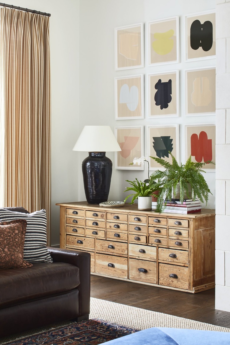 framed artwork on the wall near chest and lamp