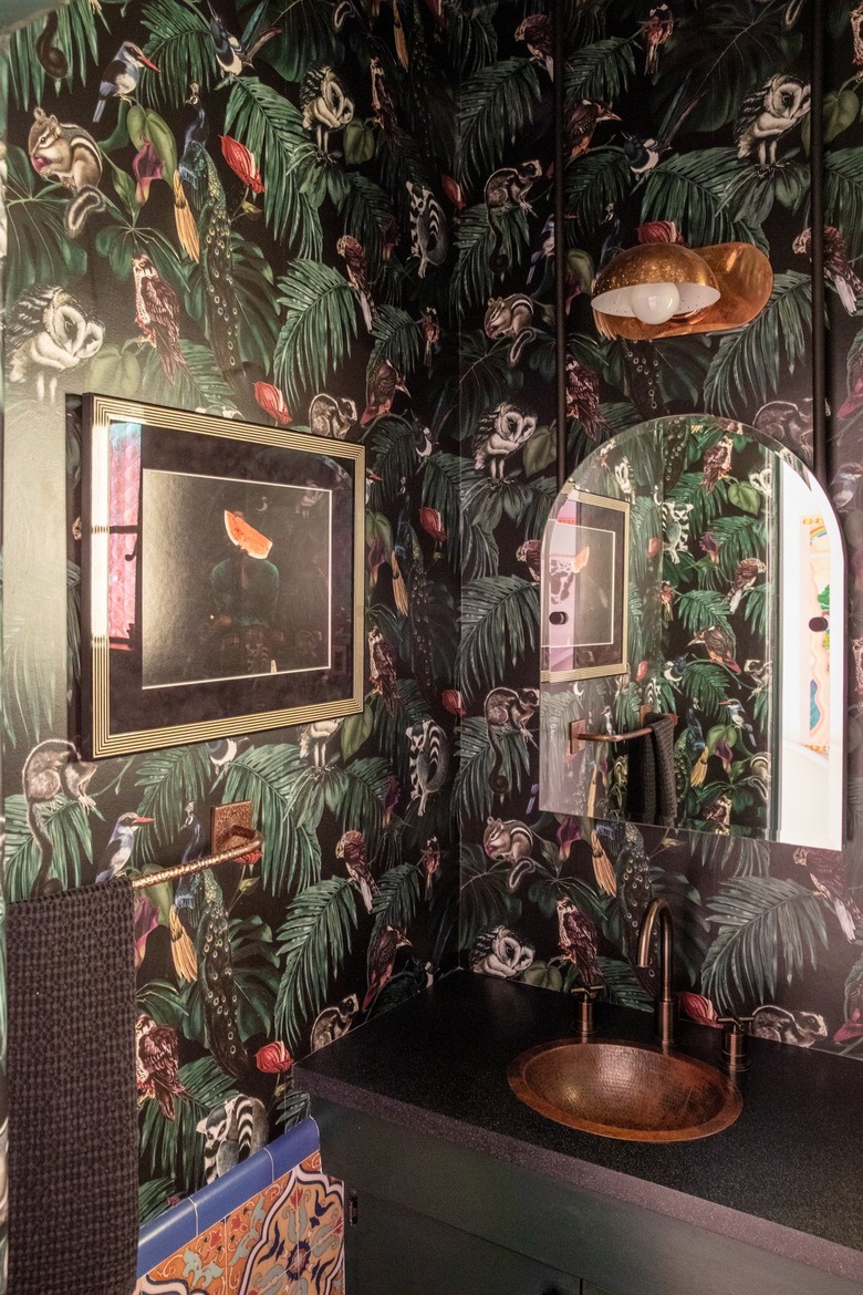 dark powder room with jungle-themed wallpaper and copper sink