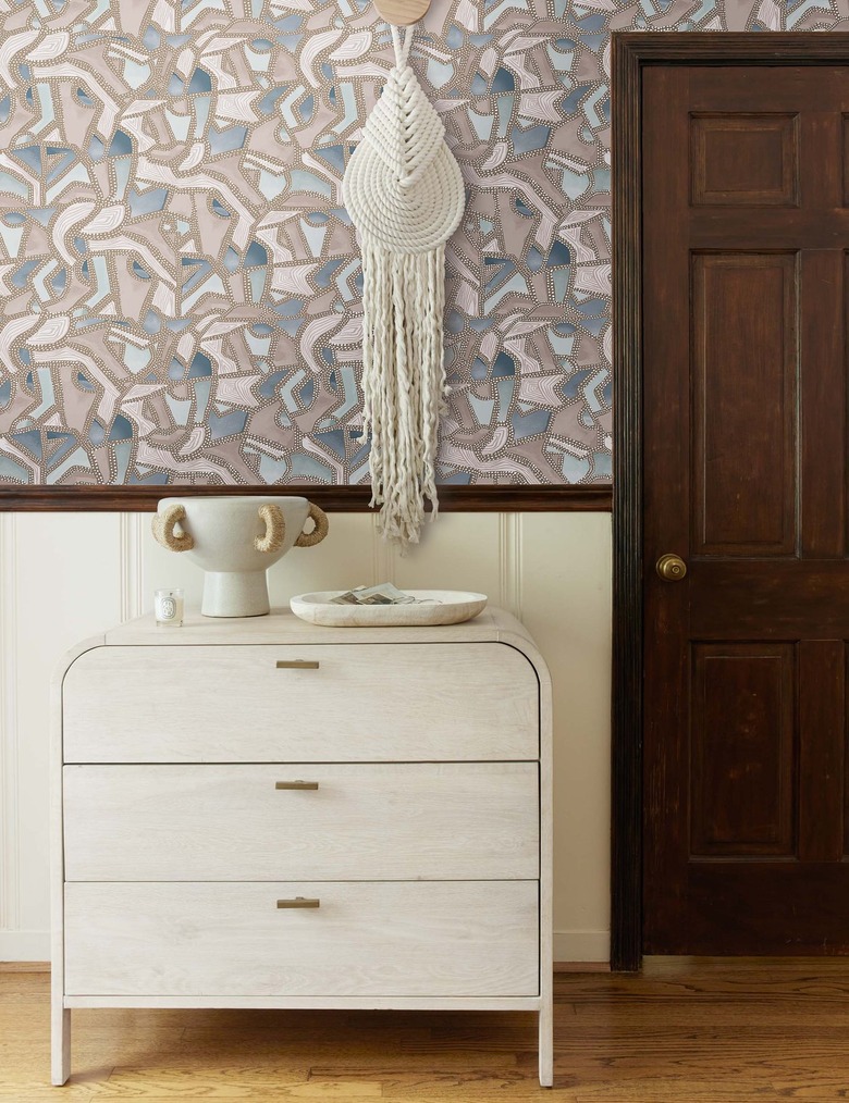 patterned wallpaper with dresser and wall hanging