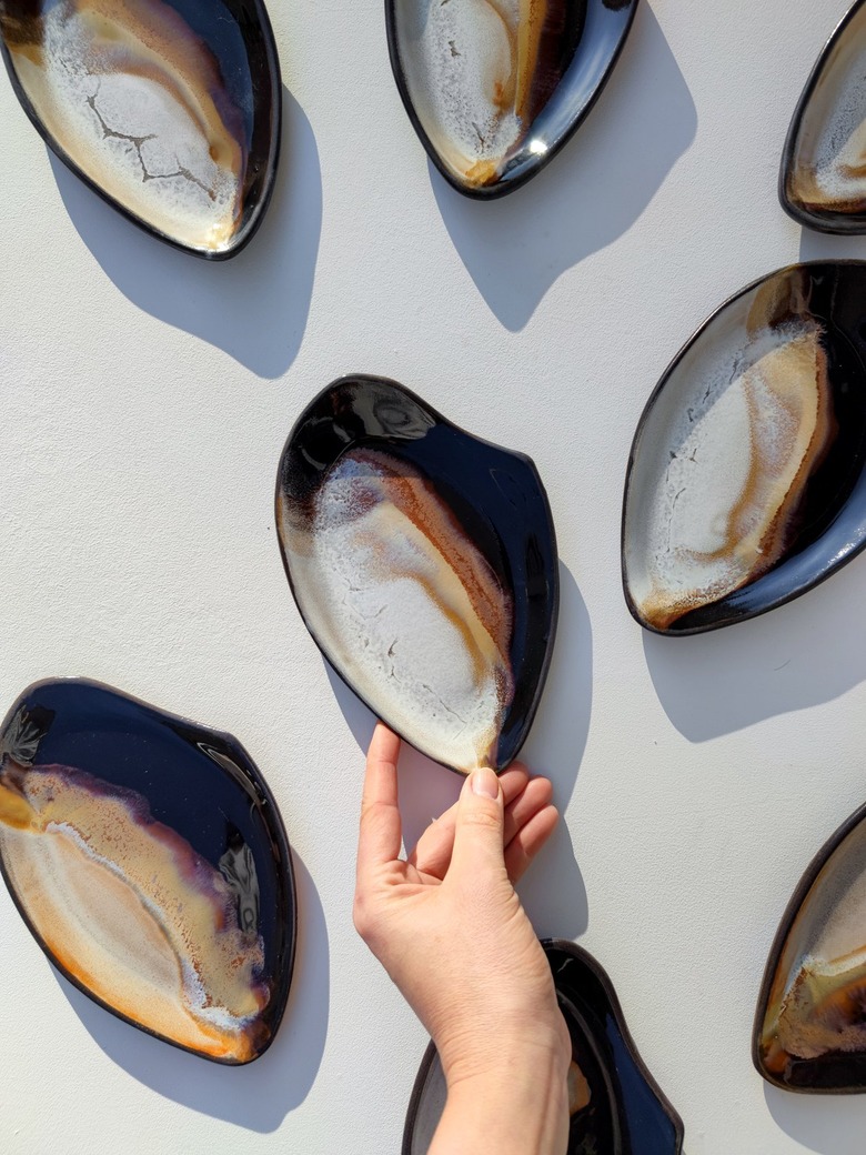 Geometric ceramic trays painted in a wash of neutral colors on a white surface.