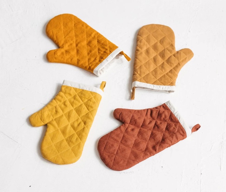 Four oven mitts in a circle in shades of yellow and orange.