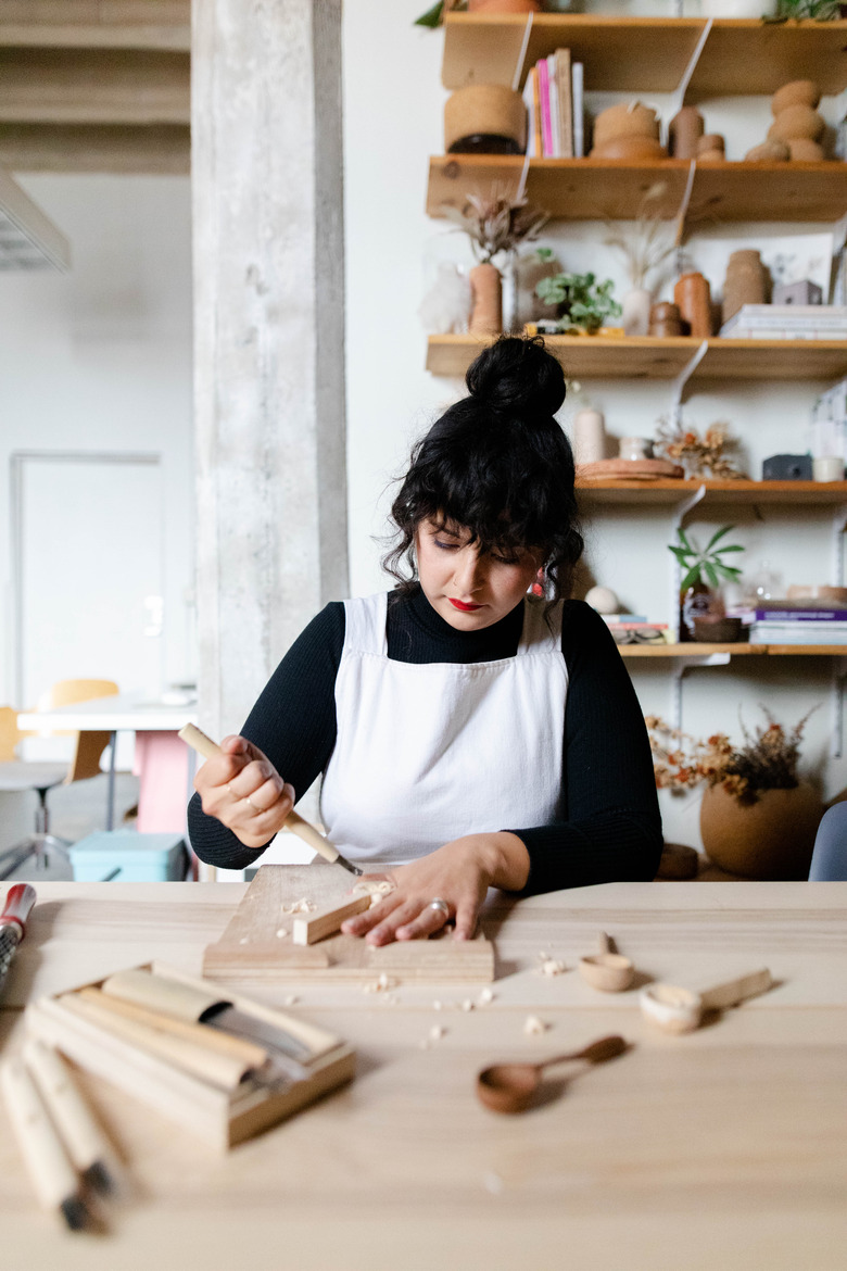 figure carving on a wooden table with shelves in the background