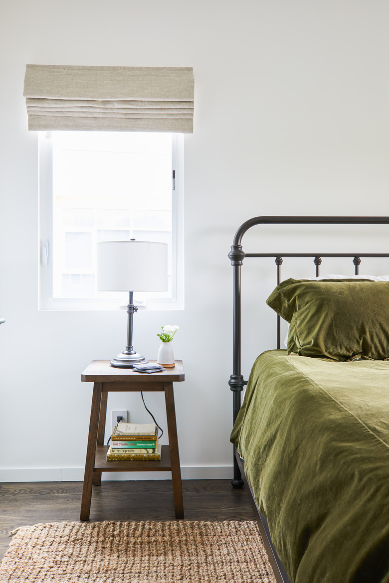 Bedroom with green bedding and rusic nightstand