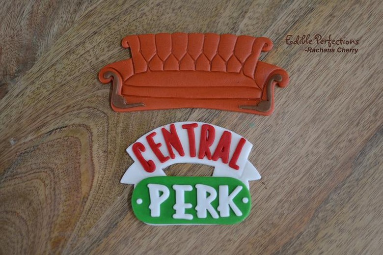 two cake topper in the shape of a couch and Central Perk logo