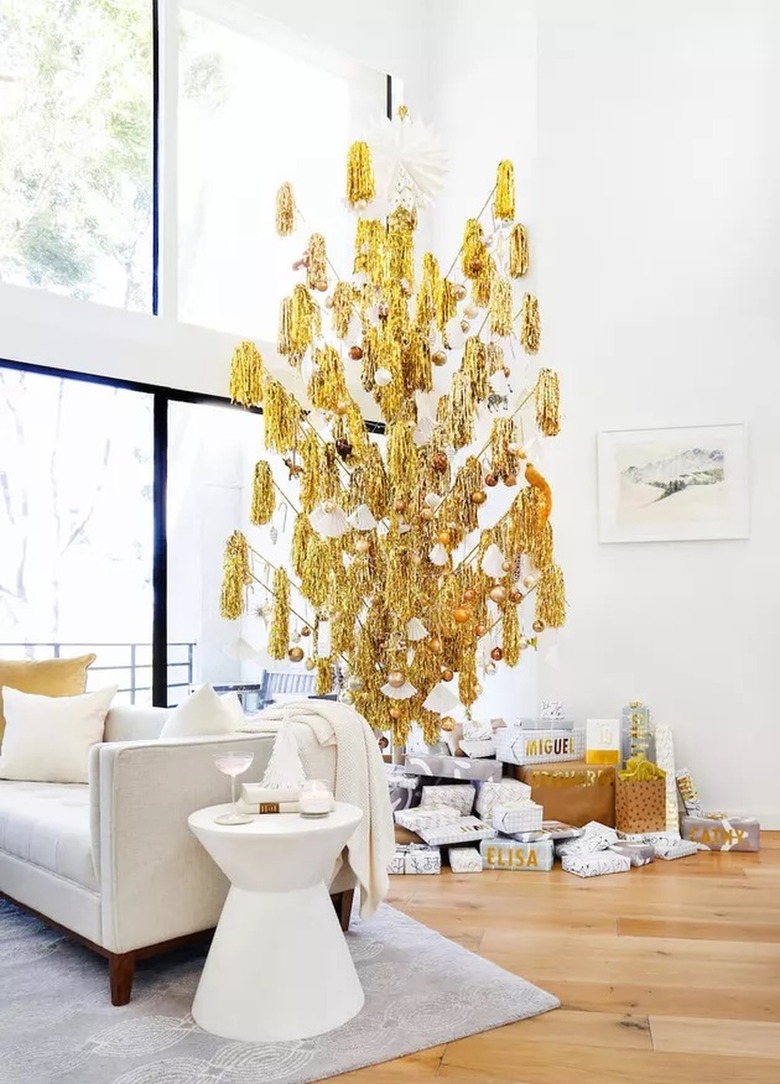 Gold pompom Christmas tree in a high-ceiling modern white living room