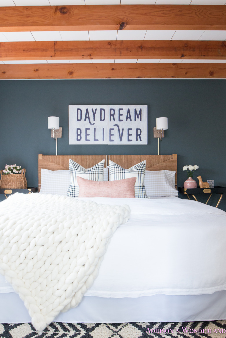 small wall lights above rattan headboard in modern farmhouse bedroom