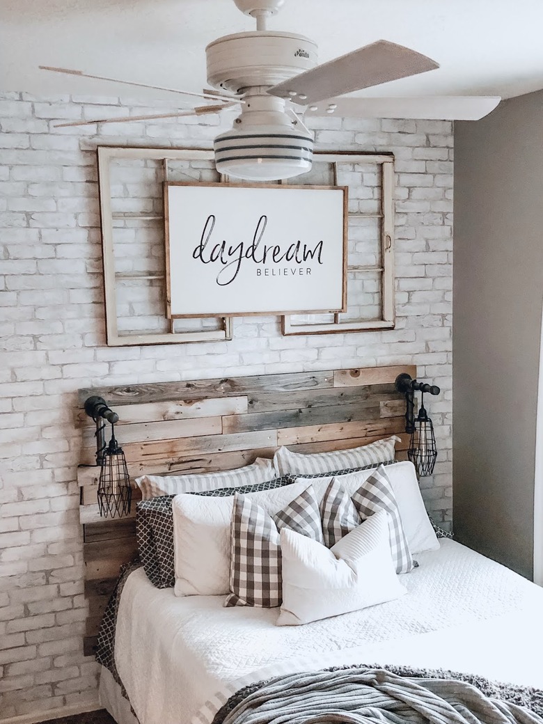 A ceiling fan in a rustic farmhouse bedroom with wooden headboard