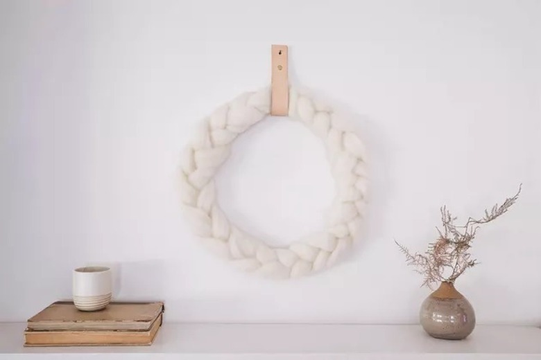braided wool wreath hanging on a white wall