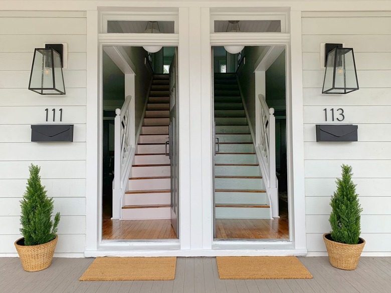 modern house numbers on white siding below wall sconces