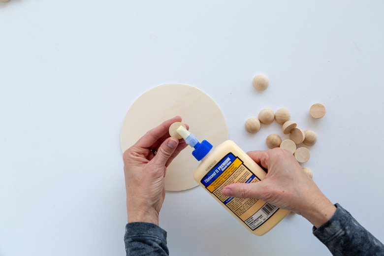 Applying wood split beads to a wood circle using wood glue.