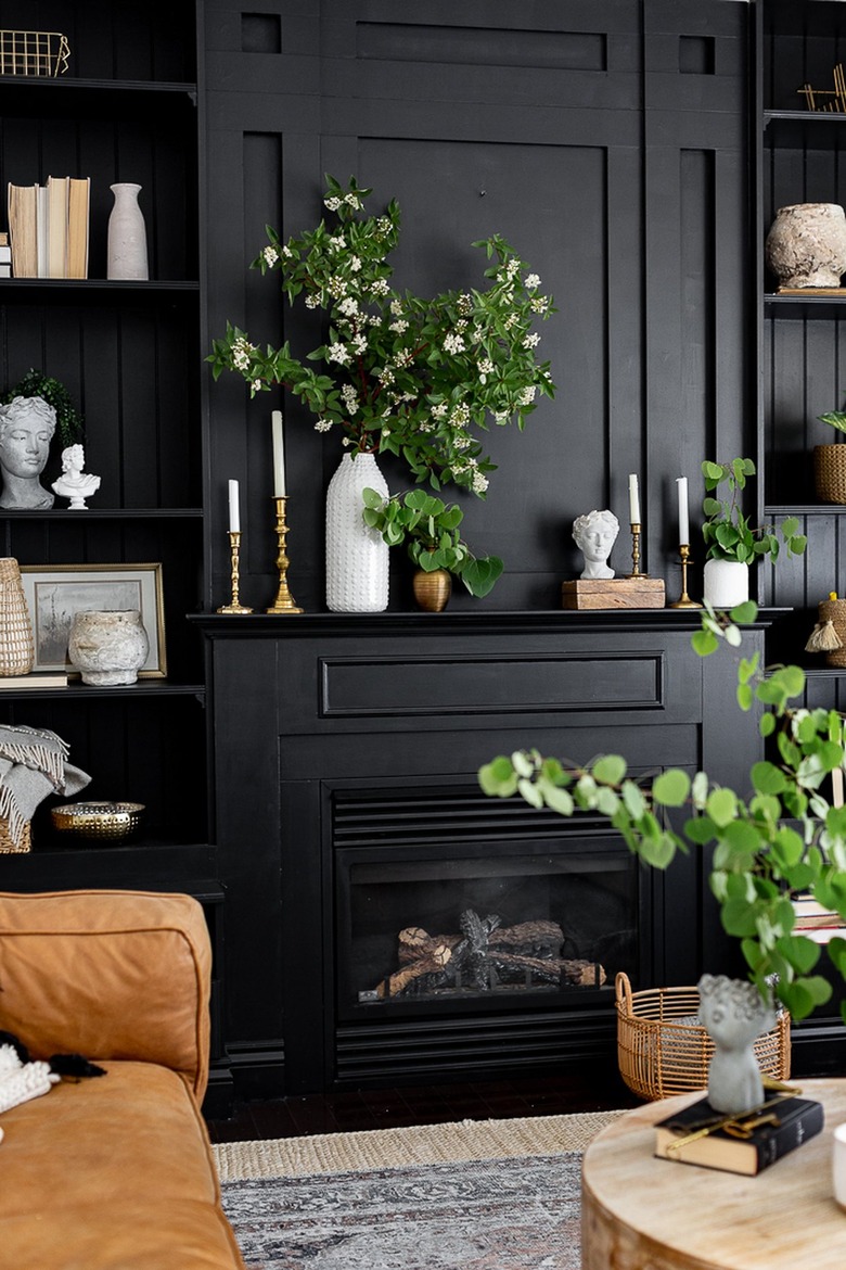 Black fireplace mantel and shelves styled with white busts