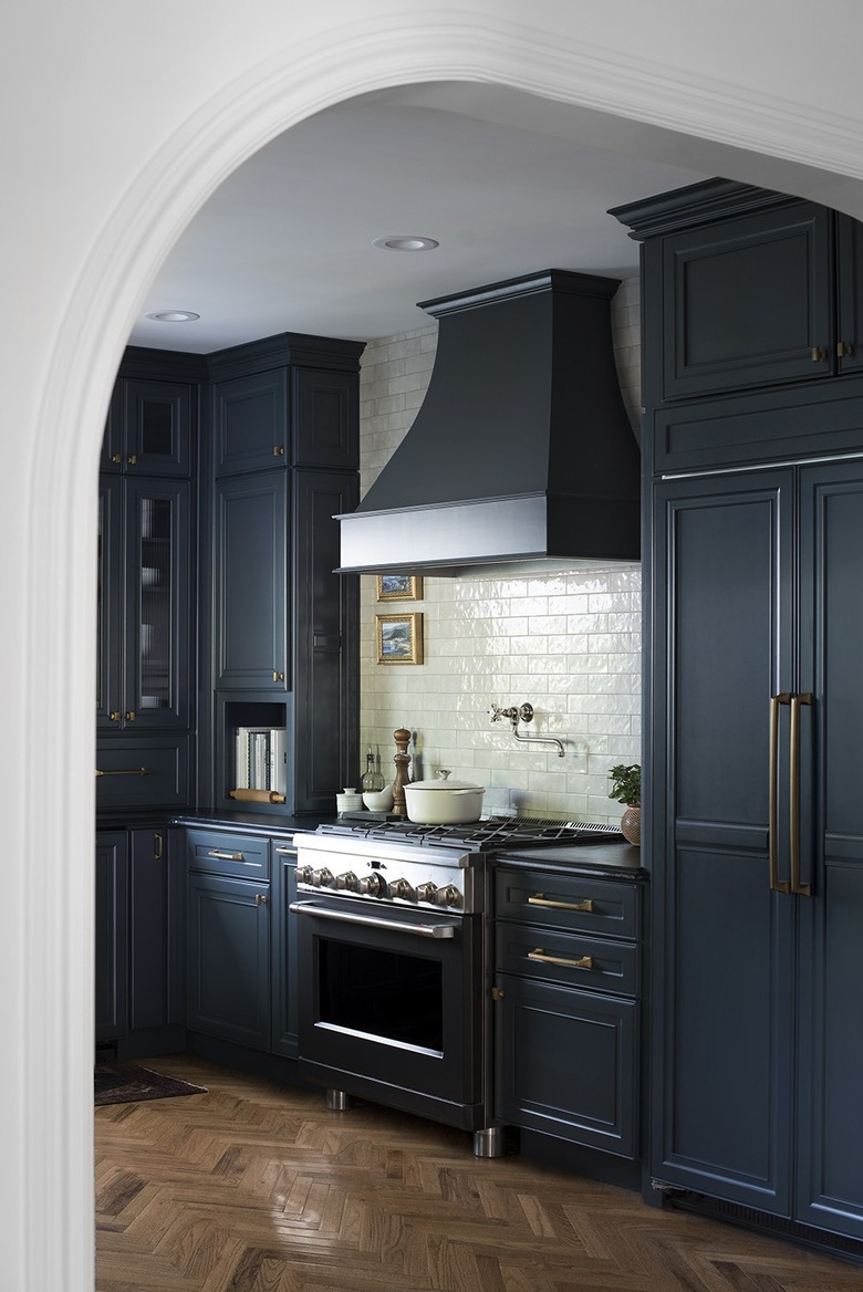 Dark navy blue kitchen color idea with white subway tile backsplash and brass hardware
