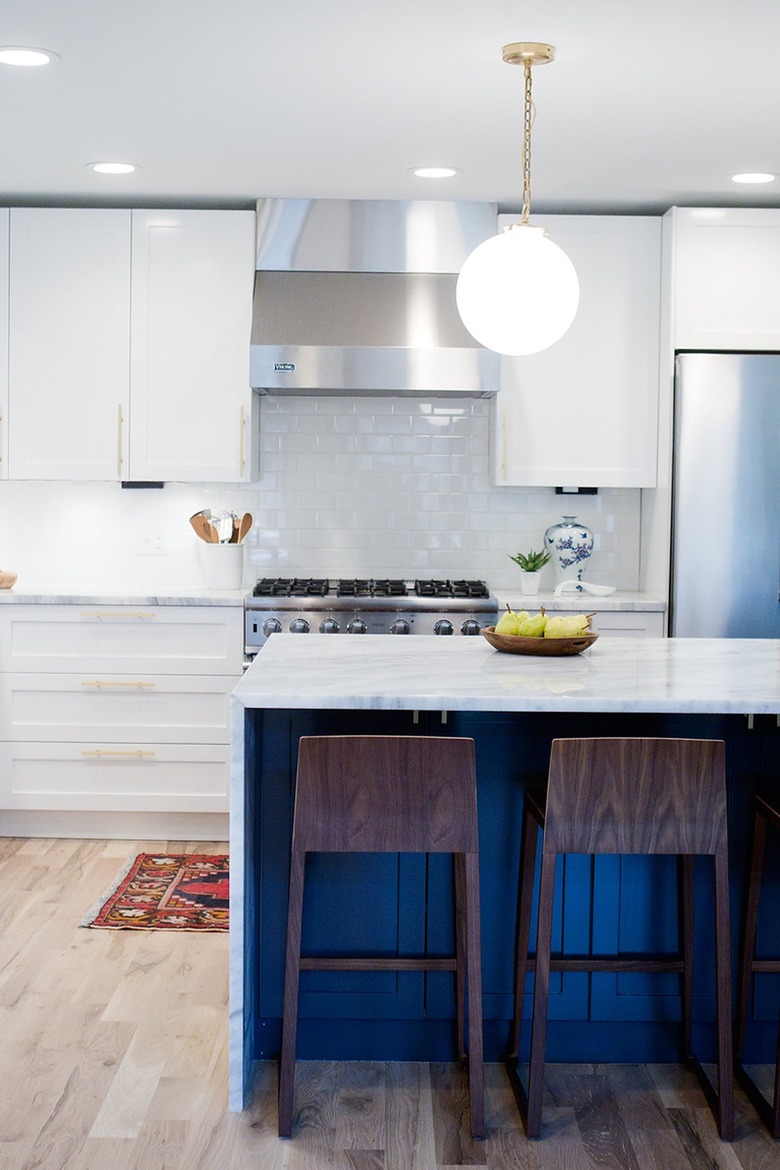 blue kitchen island with waterfall countertop and globe pendant light
