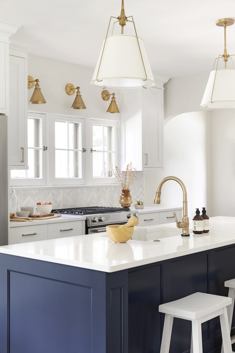 navy blue island with brass lighting and white countertop