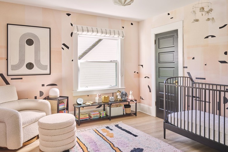 nursery with pink and black wallpaper and and graphic artwork and rug