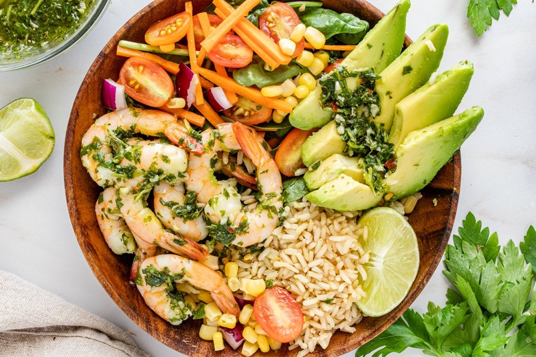 A wood bowl filled with chimichurri shrimp. rice
