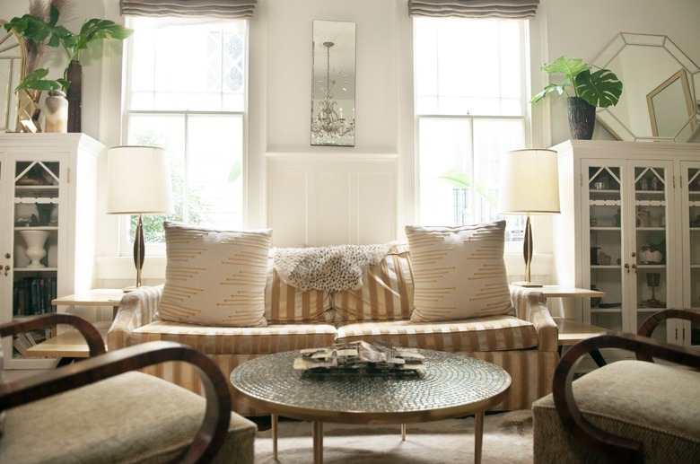 room with two chairs and coffee table and a striped couch near two large windows