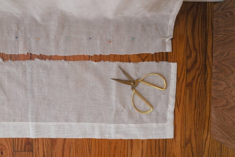 Excess curtain fabric cut off with gold scissors