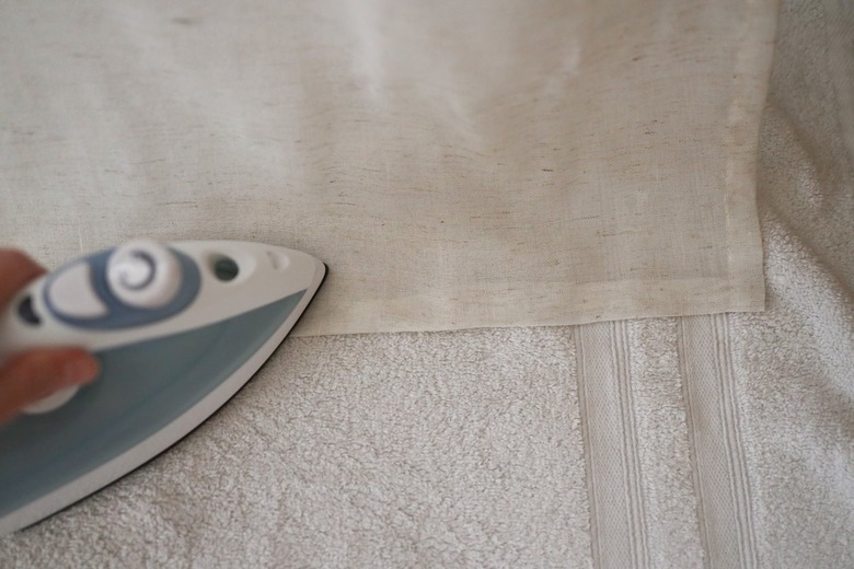 Pressing folded fabric with a hot iron and with a towel underneath the fabric