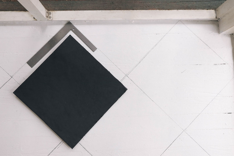 Tracing diamond pattern on floor with pencil and framing square