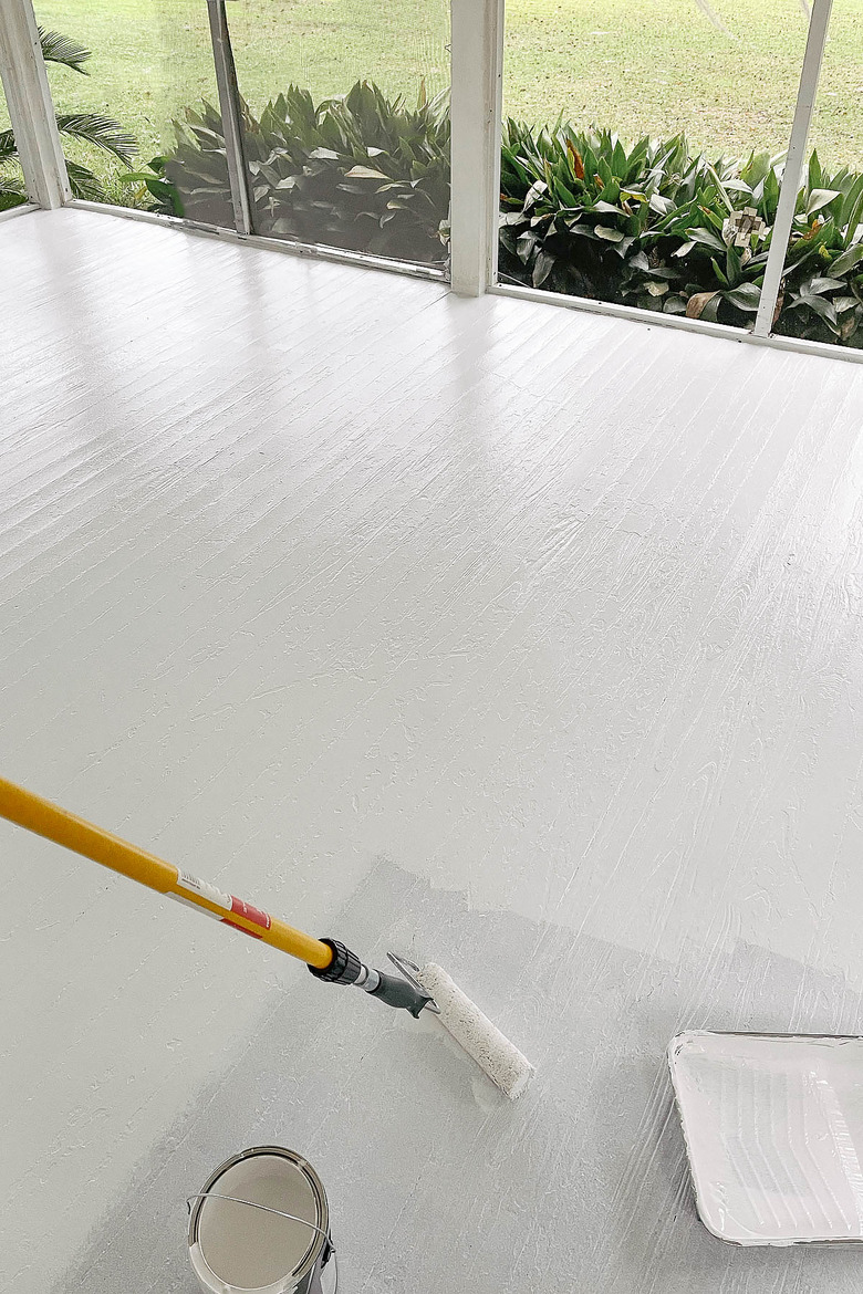 Rolling first coat of paint on wood floor with extension pole