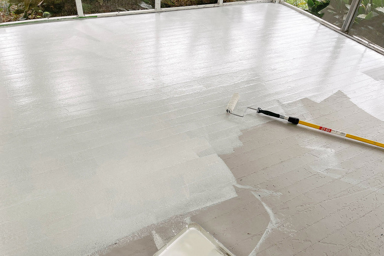 Rolling primer onto wood sunroom floor with extension pole