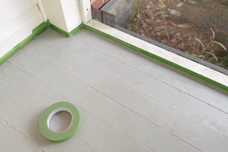 Taping painter's tape around baseboards of sunroom