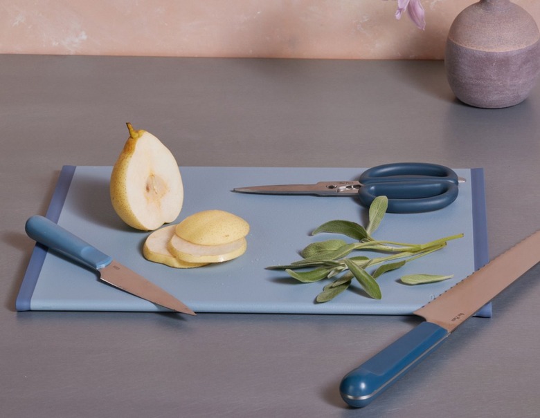 A blue cutting board with a pear and sage on top of it