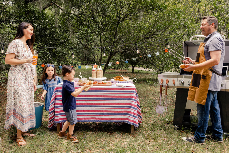 Parents and two small kids grilling and enjoying hot dog bar