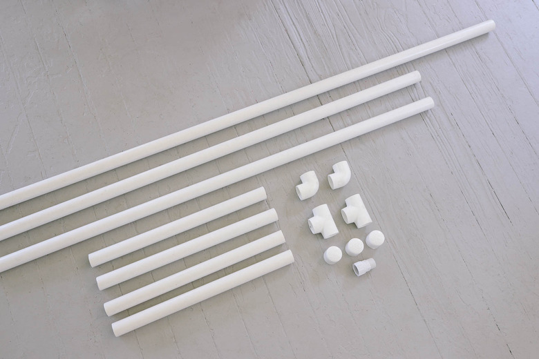 PVC pipe cut to various sizes laid next to elbow and tee connectors and caps