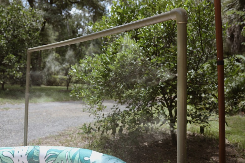 Green PVC pipe water mister over an inflatable pool