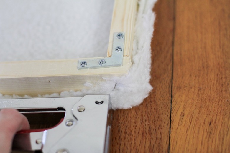 Wood frame with flat screw brace and staple gun stapling white shearling