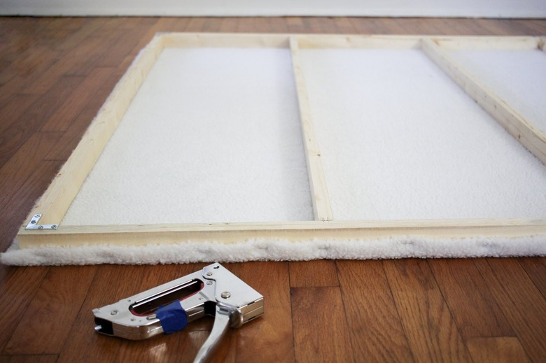 Wood frame with stapled white shearling next to staple gun