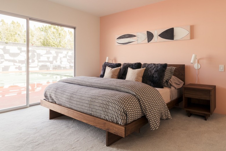 Pink wall bedroom with black and neutral bedding. A wood night stand