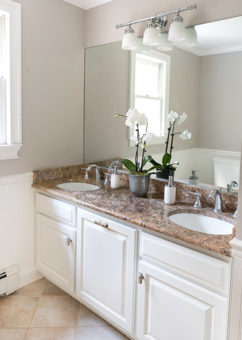 Painted bathroom cabinets before and after featuring white cabinets and stone countertop