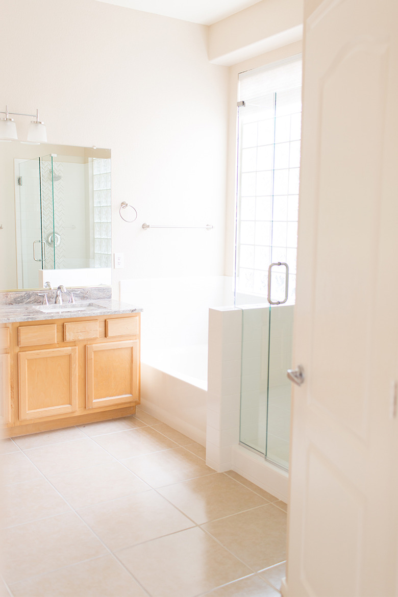 Painted bathroom cabinets before and after featuring light wood cabinets and beige floor tile