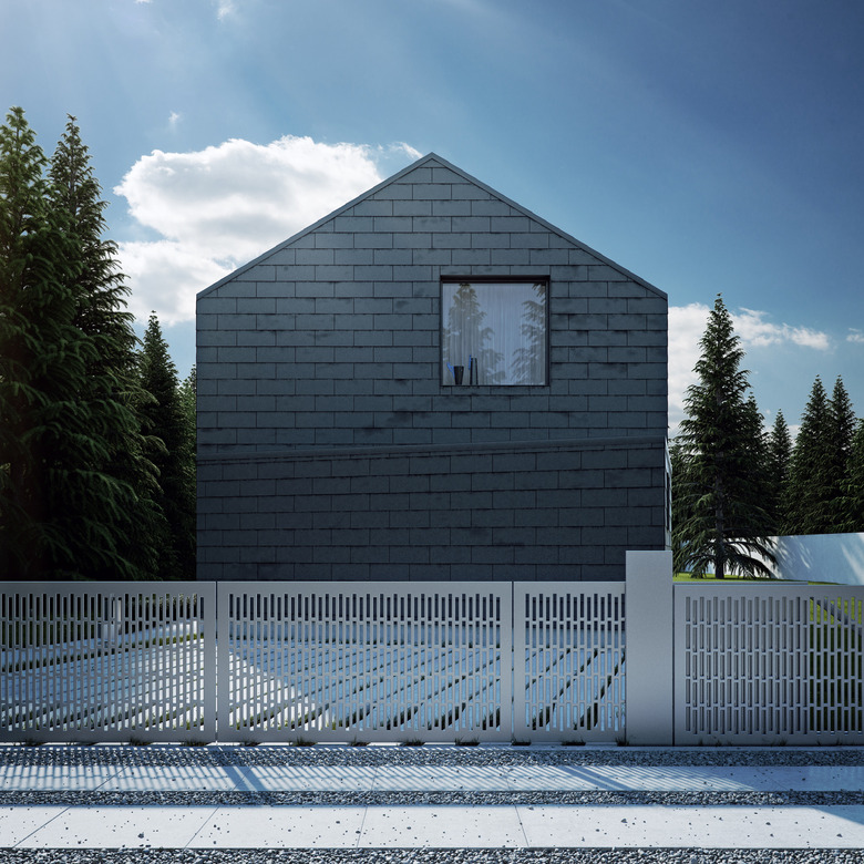 painting exterior brick on black brick modern house with metal gate and pine trees.