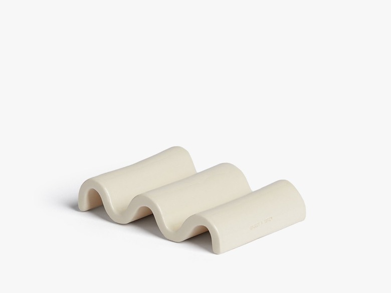 A beige wavy stone soap dish on a white background.