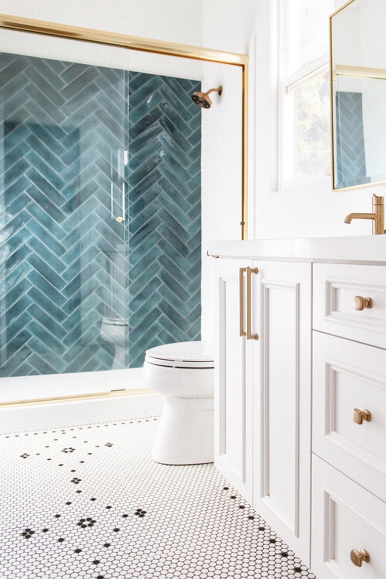 white bathroom with teal herringbone tile shower and black and white penny tile mosaic pattern floor